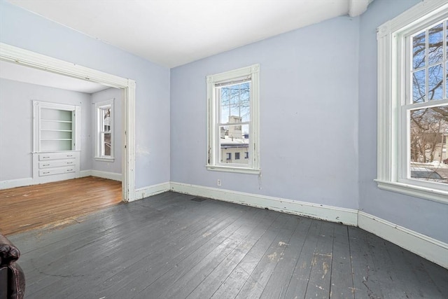 empty room with dark wood-type flooring and baseboards