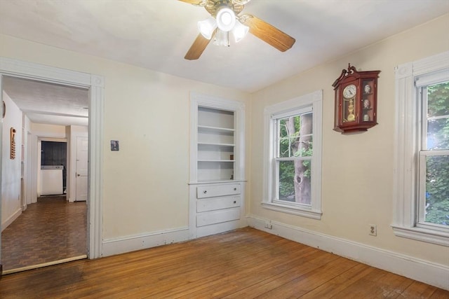 unfurnished bedroom featuring multiple windows, baseboards, and wood finished floors