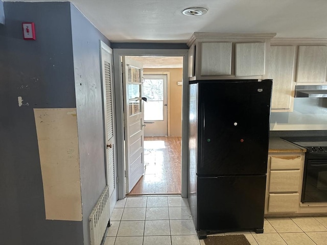 kitchen with dark countertops, black appliances, light tile patterned flooring, and exhaust hood