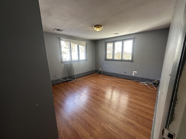unfurnished room featuring plenty of natural light, wood finished floors, and visible vents
