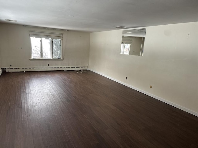 unfurnished room featuring baseboards, visible vents, a baseboard heating unit, and dark wood-style flooring