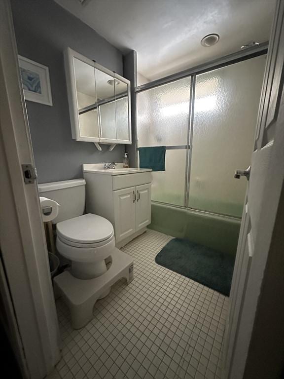 bathroom with tile patterned flooring, vanity, toilet, and bath / shower combo with glass door