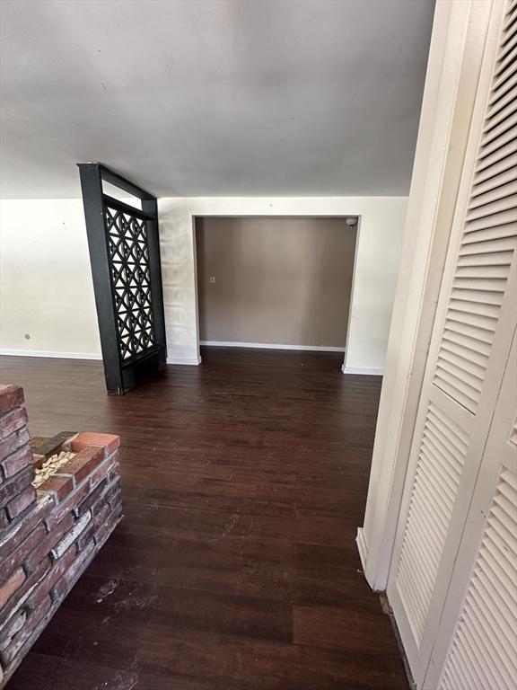 unfurnished living room with wood finished floors and baseboards