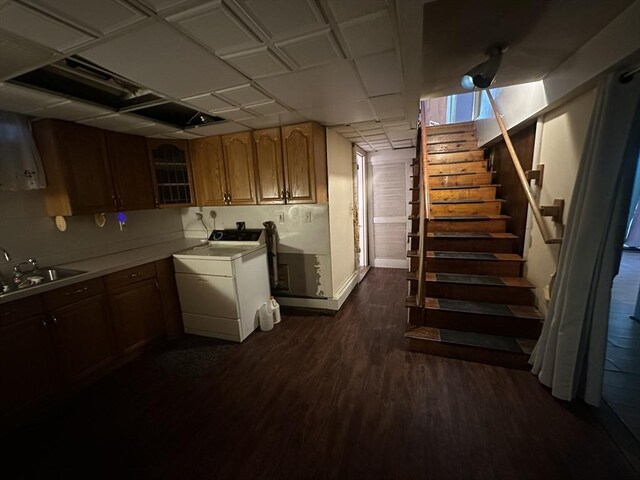 kitchen featuring dark wood-style flooring, a sink, light countertops, washer / clothes dryer, and glass insert cabinets