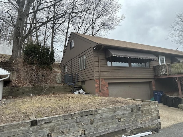 view of home's exterior with concrete driveway, brick siding, an attached garage, and central air condition unit