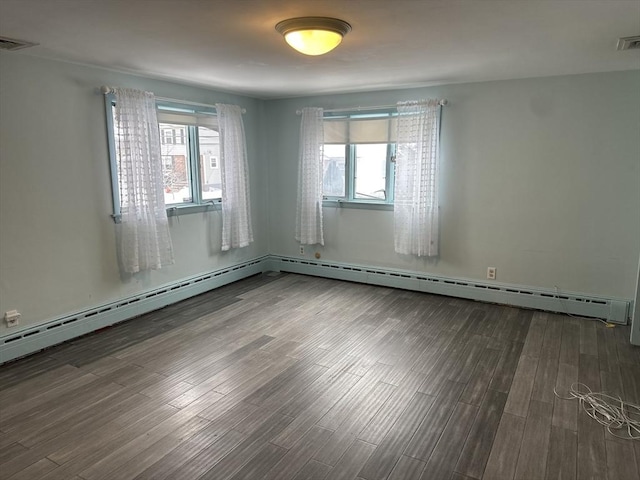 empty room featuring a wealth of natural light, visible vents, and wood finished floors