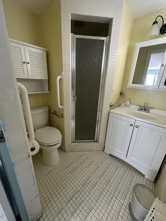 bathroom featuring a stall shower, vanity, toilet, and tile patterned floors