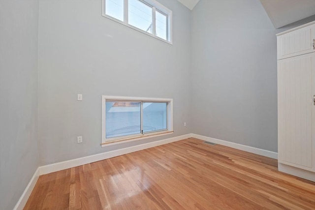 unfurnished room with lofted ceiling and light hardwood / wood-style floors