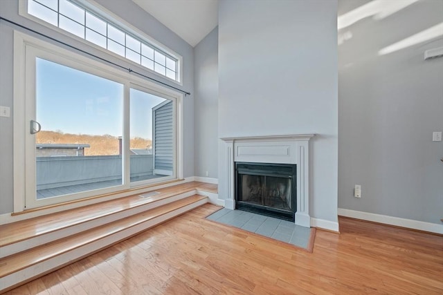 unfurnished living room featuring a towering ceiling and light hardwood / wood-style floors