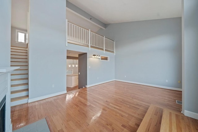 unfurnished living room featuring beam ceiling, high vaulted ceiling, and light wood-type flooring