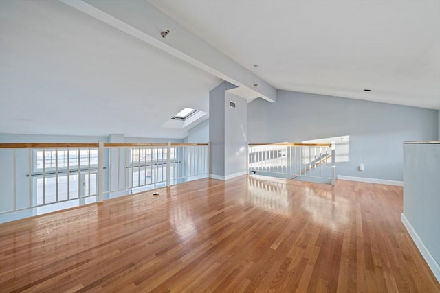 interior space with light hardwood / wood-style floors and vaulted ceiling with skylight