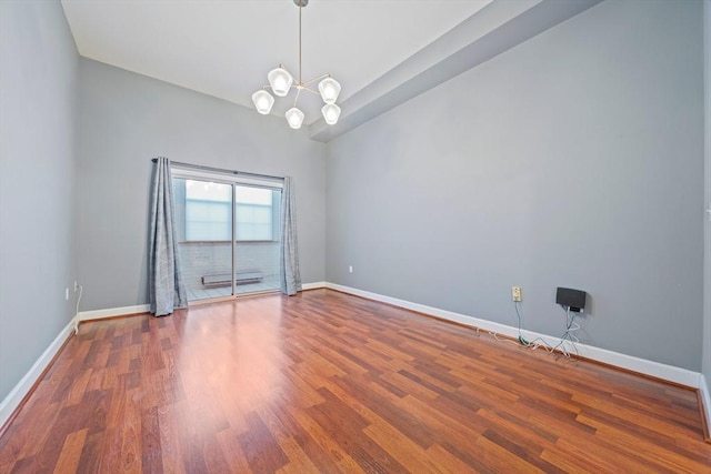 empty room featuring a notable chandelier and wood-type flooring