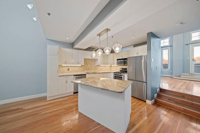 kitchen featuring appliances with stainless steel finishes, a kitchen island, pendant lighting, decorative backsplash, and white cabinets