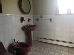 bathroom featuring baseboard heating and tile walls