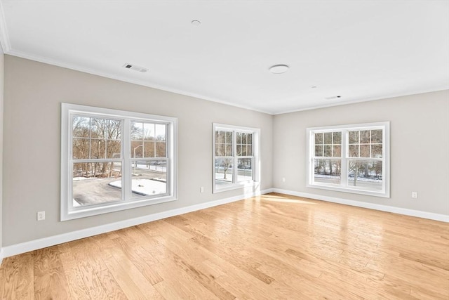 spare room featuring crown molding, wood finished floors, visible vents, and baseboards