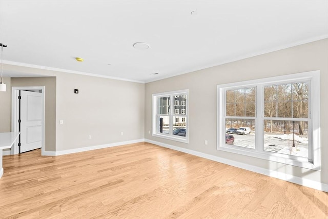 spare room featuring ornamental molding, light wood-type flooring, and baseboards