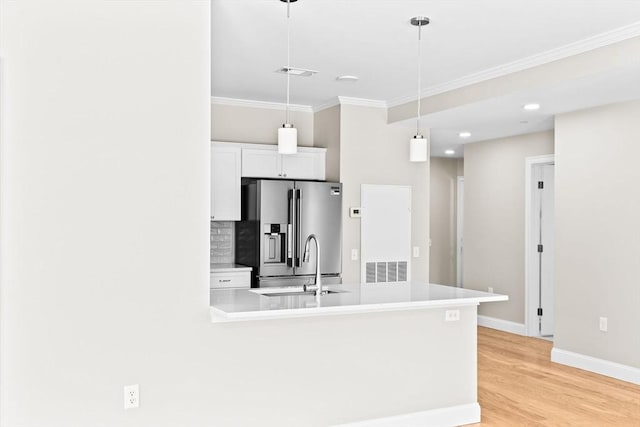 kitchen with stainless steel fridge, visible vents, white cabinets, light wood-style flooring, and ornamental molding