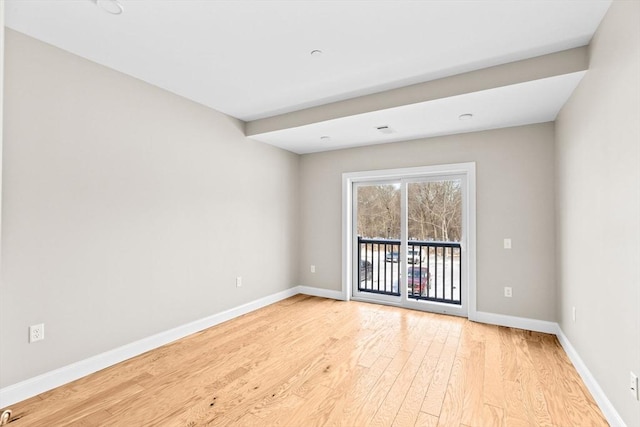 spare room featuring light wood-type flooring and baseboards