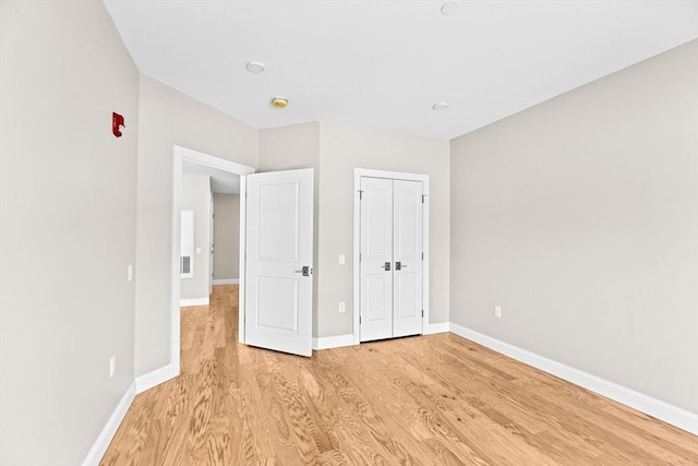 unfurnished bedroom with baseboards, a closet, and light wood-style floors