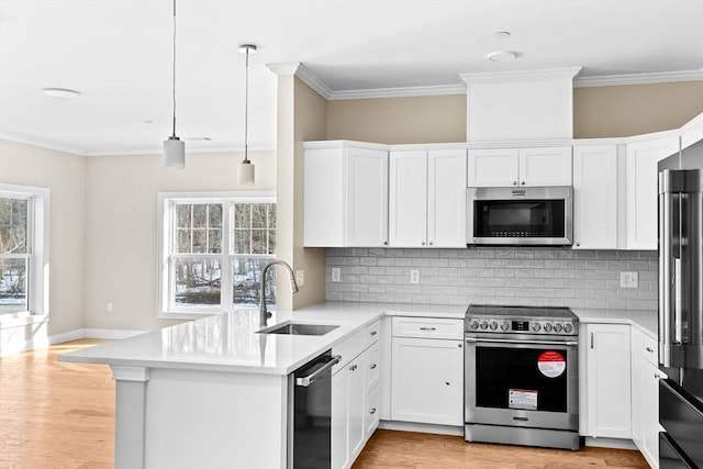 kitchen with stainless steel appliances, light countertops, a sink, and a peninsula