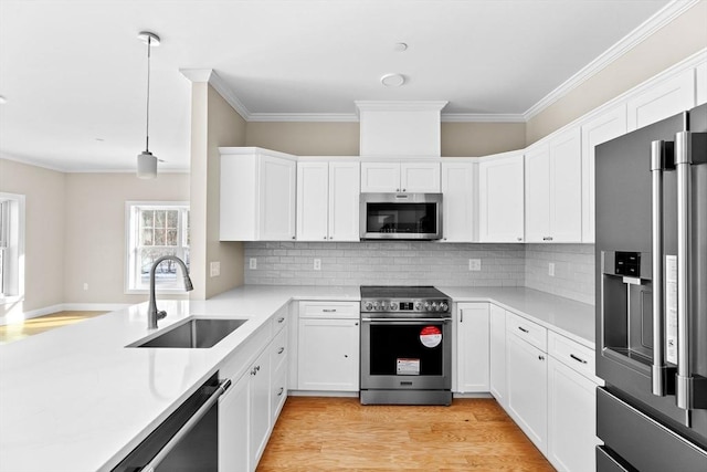 kitchen with light wood finished floors, white cabinets, appliances with stainless steel finishes, light countertops, and a sink