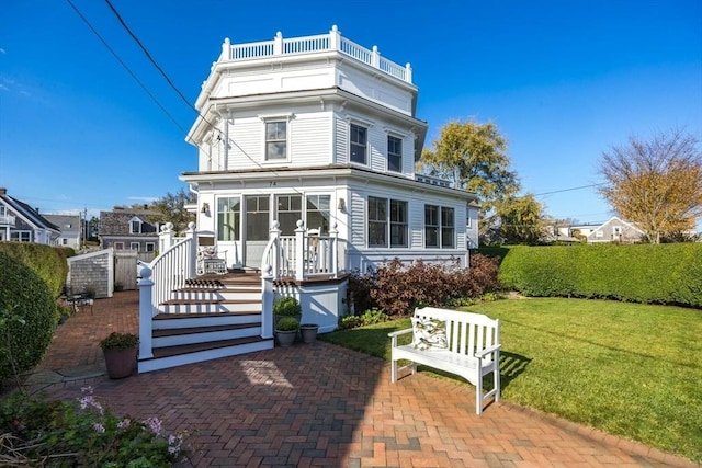 view of front of home with a balcony, a patio, and a front yard