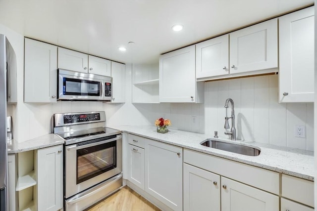 kitchen with light stone countertops, white cabinetry, sink, and appliances with stainless steel finishes