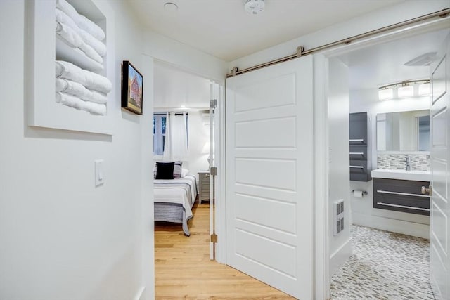 hallway featuring a barn door and light hardwood / wood-style floors