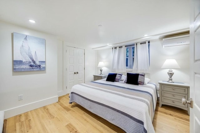 bedroom featuring a wall mounted air conditioner, light wood-type flooring, and a closet