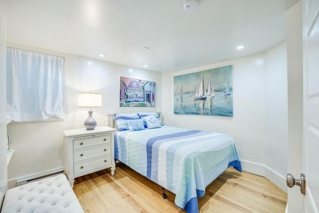 bedroom featuring baseboard heating and light hardwood / wood-style flooring