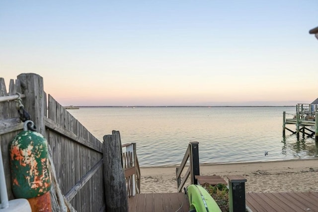 view of dock with a water view and a beach view