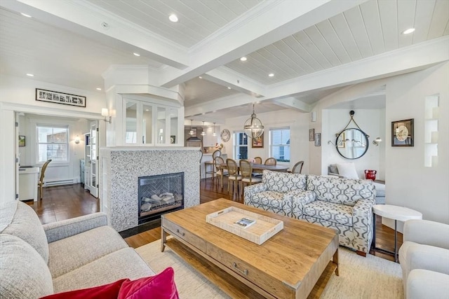 living room featuring beam ceiling, light hardwood / wood-style floors, plenty of natural light, and a tiled fireplace