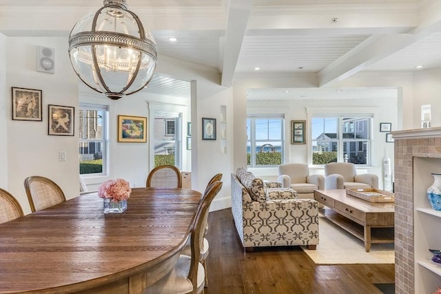 dining space featuring a notable chandelier, beam ceiling, dark hardwood / wood-style floors, and a fireplace