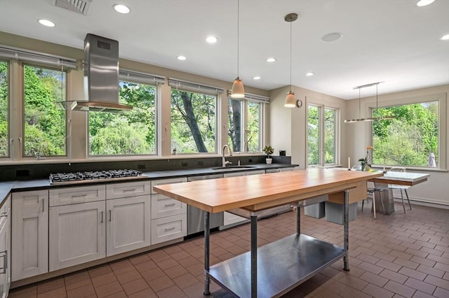kitchen with exhaust hood, wooden counters, stainless steel gas cooktop, a sink, and pendant lighting