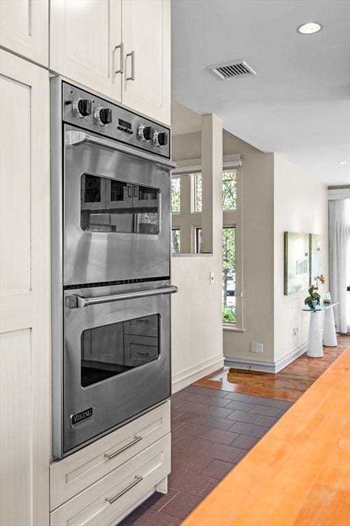 kitchen featuring double oven, baseboards, recessed lighting, light countertops, and white cabinets