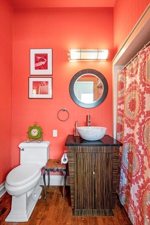 bathroom with wood finished floors, toilet, vanity, baseboards, and a shower with shower curtain
