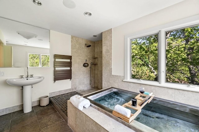 bathroom featuring a tile shower, baseboards, and a sink