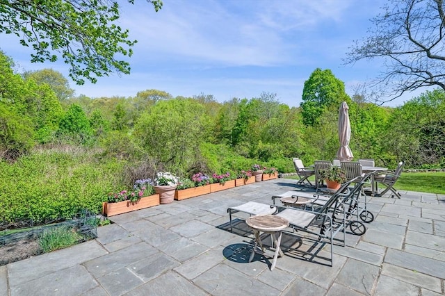 view of patio / terrace featuring outdoor dining area and a view of trees