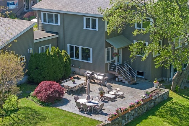 rear view of property featuring a patio area, a yard, and a shingled roof