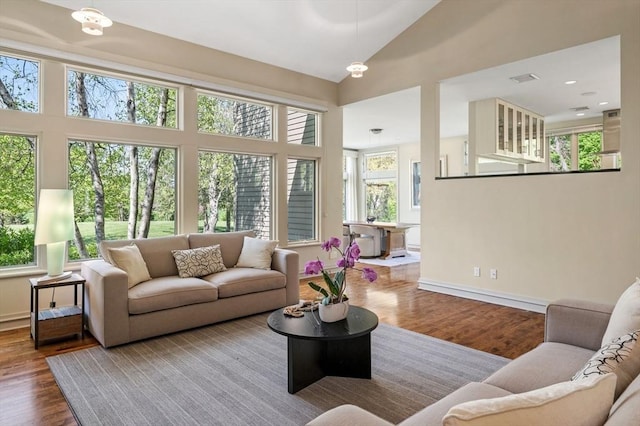 living area featuring wood finished floors, baseboards, and a towering ceiling