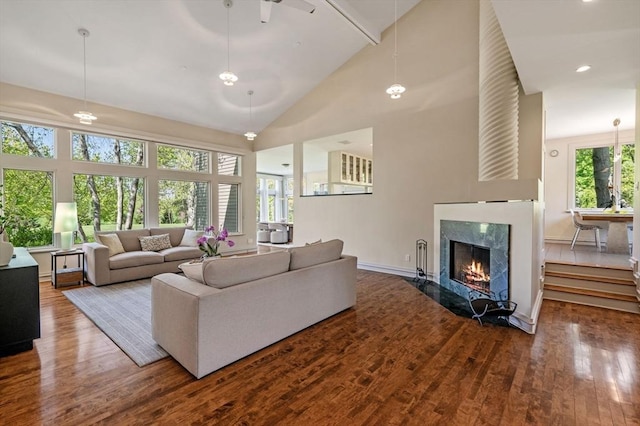 living area with high vaulted ceiling, wood finished floors, a high end fireplace, baseboards, and beamed ceiling