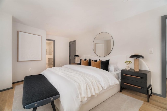 bedroom with ensuite bathroom and light hardwood / wood-style floors