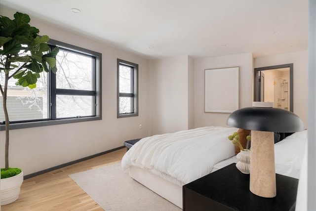 bedroom featuring connected bathroom and light hardwood / wood-style floors