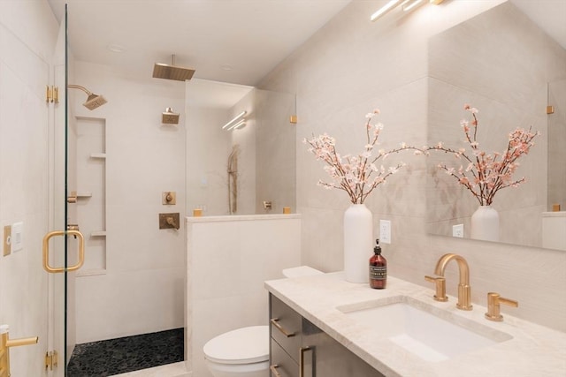 bathroom with vanity, toilet, tile walls, and a shower with shower door