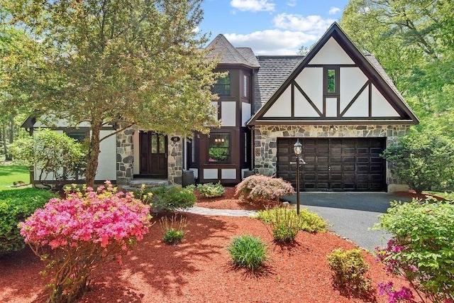 tudor house with stone siding, asphalt driveway, stucco siding, and a shingled roof