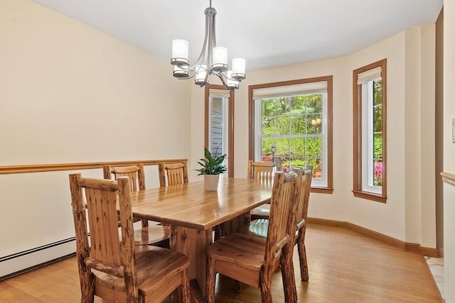 dining room with a baseboard heating unit, light wood-style flooring, a chandelier, and baseboards