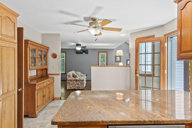 kitchen with ceiling fan, light stone counters, and light tile patterned floors
