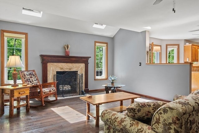 living area with plenty of natural light, wood finished floors, baseboards, and a premium fireplace