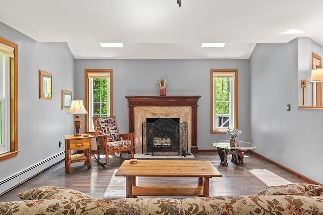 living area with a baseboard radiator, wood finished floors, a fireplace, and baseboards