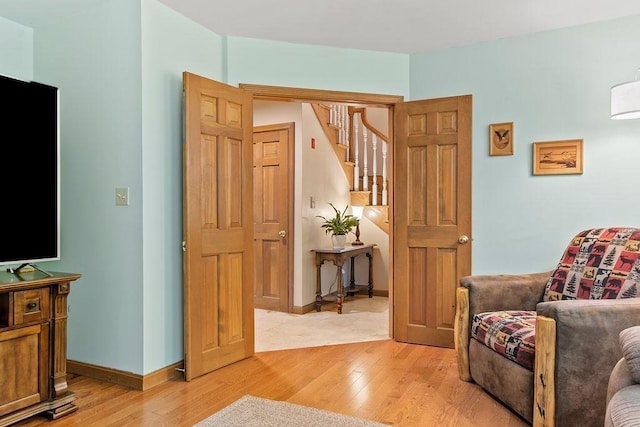 sitting room with light wood-style floors, stairs, and baseboards